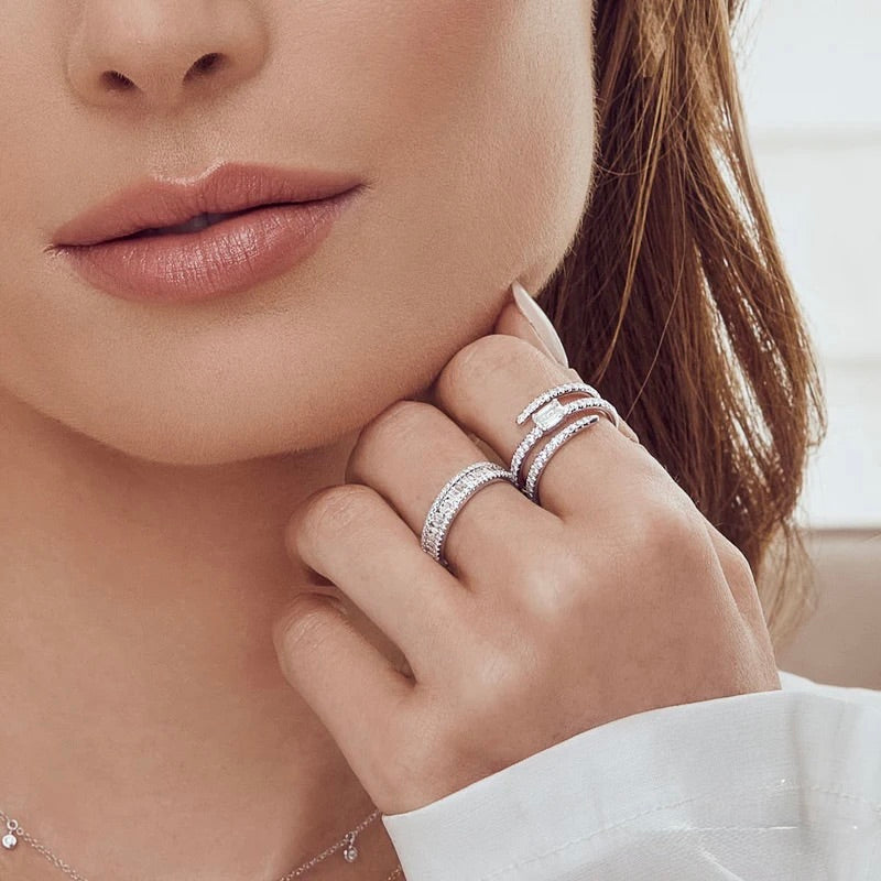 Close-up of a woman's hand wearing multiple diamond rings with a blurred background